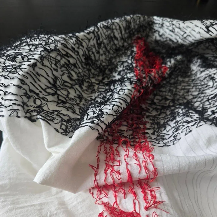 La mesa del taller: telas, hilo negro y rojo